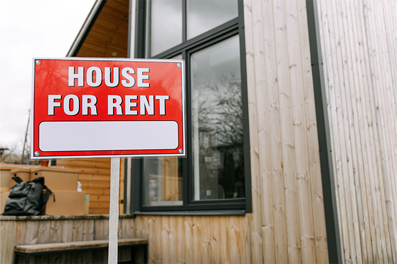 Gebäude mit einem roten Schild davor, auf dem House for Rent steht.